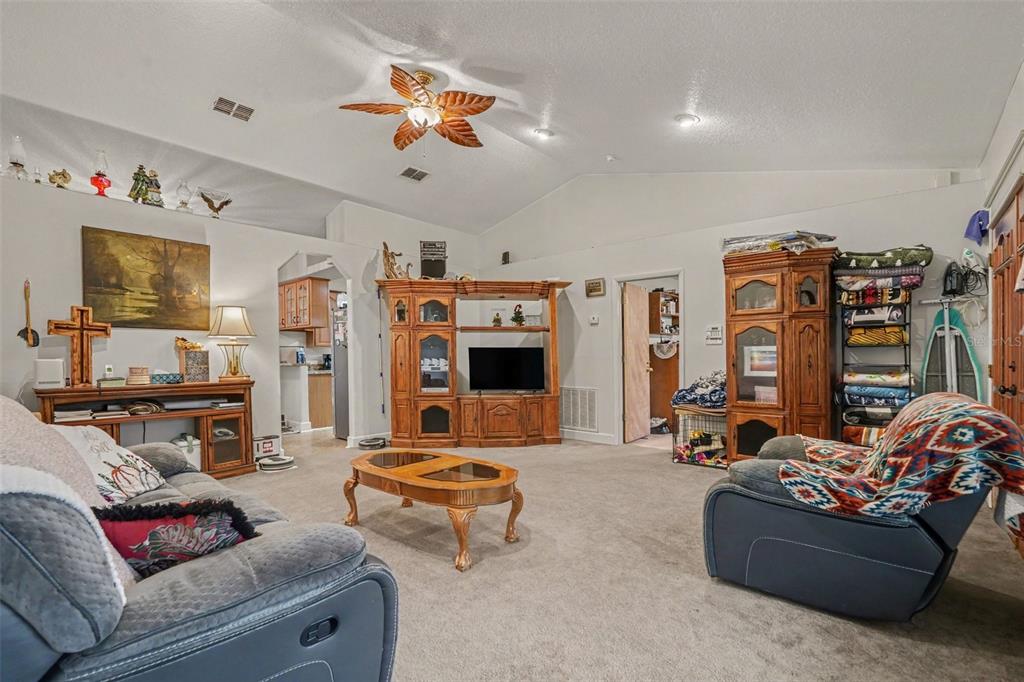 A living room with carpeted floors, a vaulted ceiling, a ceiling fan, and wooden furniture — 9172 KEDRONE DRIVE, WEBSTER, FL
