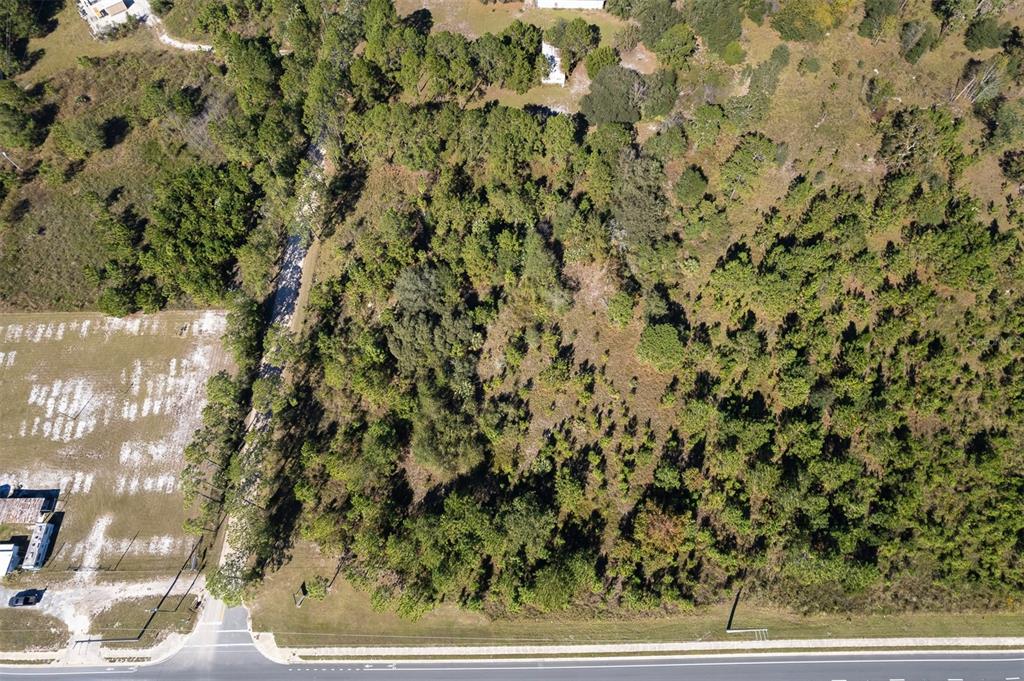 An aerial view shows a vacant, wooded lot bordered by a road and a cleared area — 108 WILLIS ROAD, INTERLACHEN, FL