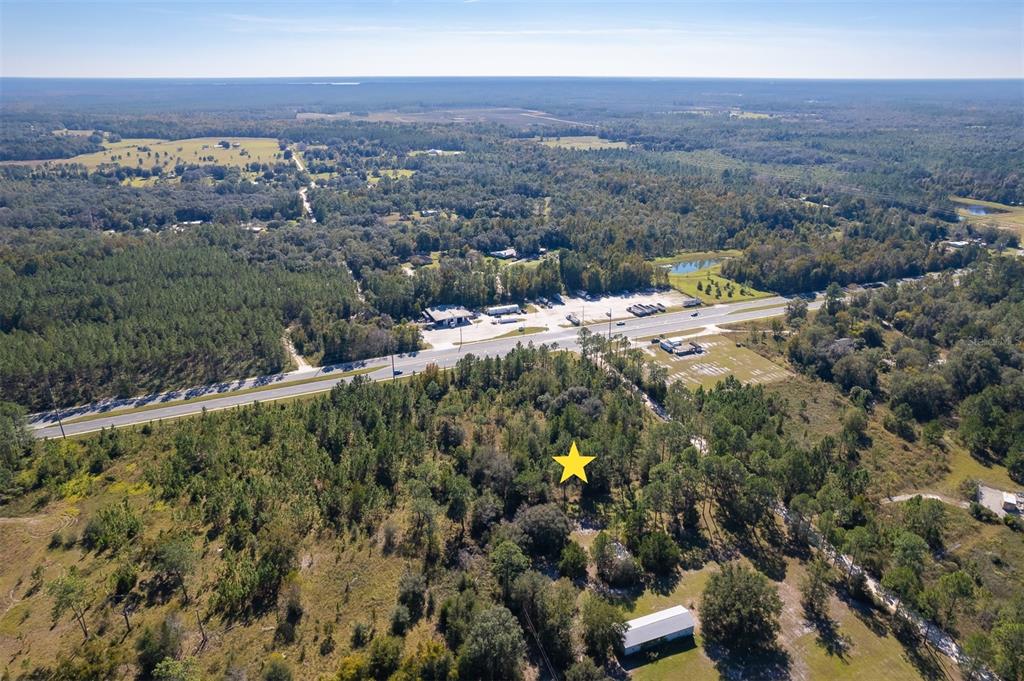 An aerial view shows a wooded lot marked with a yellow star near a highway — 108 WILLIS ROAD, INTERLACHEN, FL