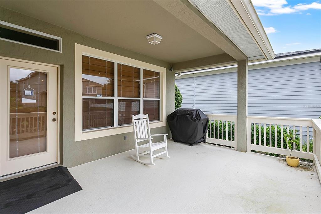 A covered patio features a white rocking chair, a grill, and a white railing — 6712 THORNHILL CIRCLE, WINDERMERE, FL