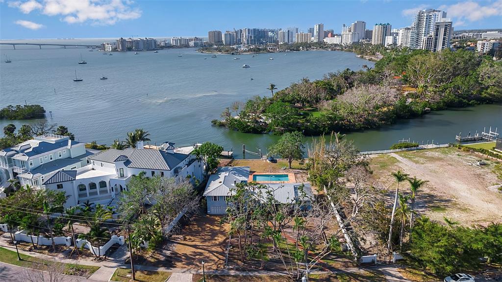 An aerial view shows waterfront homes, a swimming pool, and a large vacant lot — 1479 BAY POINT DRIVE, SARASOTA, FL