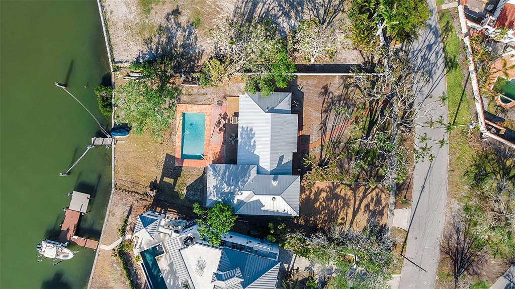 An aerial view shows a house with a metal roof, swimming pool, and private boat dock — 1479 BAY POINT DRIVE, SARASOTA, FL