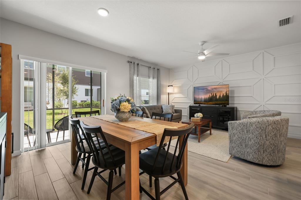 A dining area and living room with wood-look tile floors and a geometric accent wall — 14937 HARVEST STREET, ORLANDO, FL