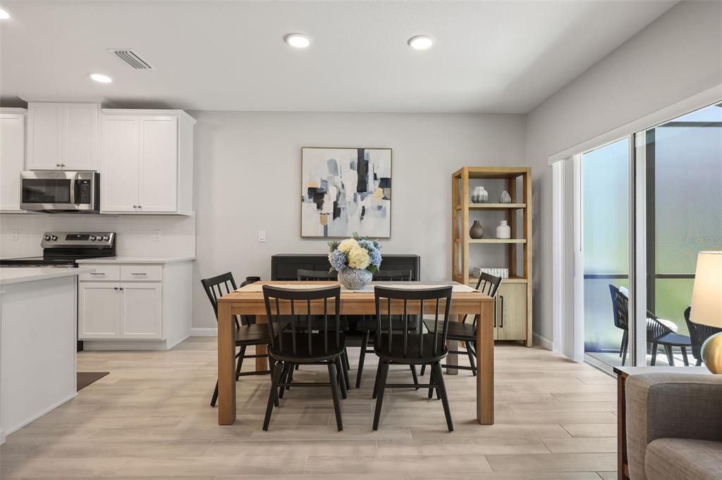 A dining area with a wooden table, black chairs, and white kitchen cabinets nearby — 14937 HARVEST STREET, ORLANDO, FL