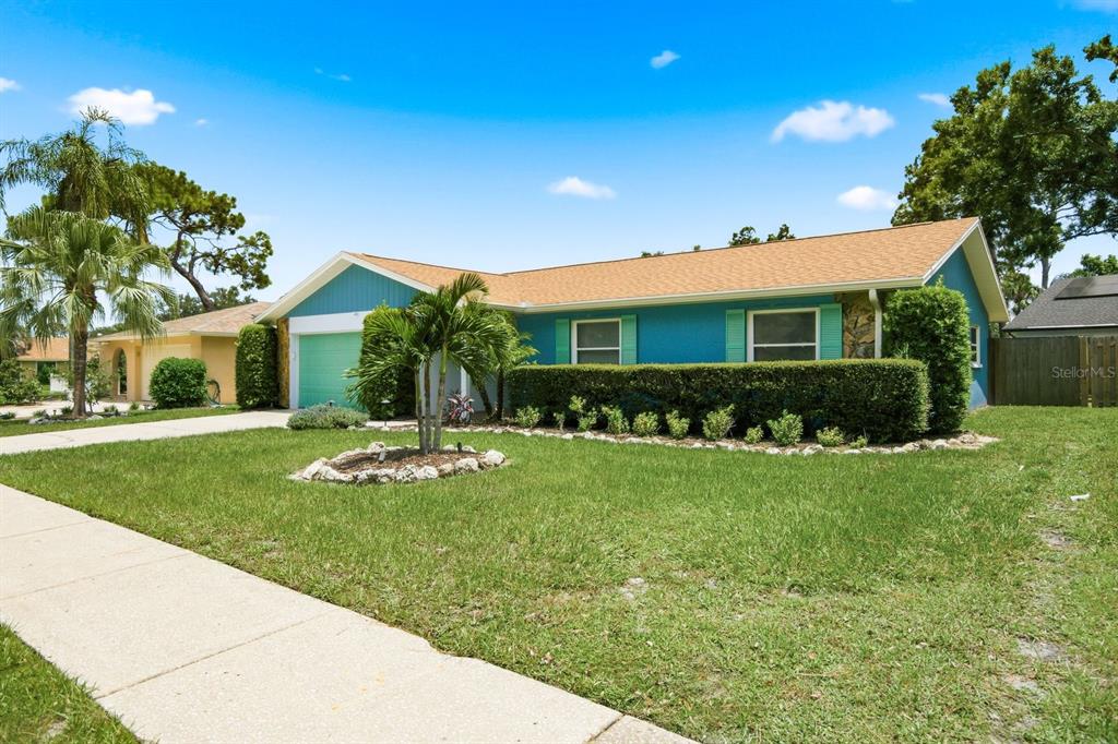 A blue single-story house with a tan roof, a green garage door, and front landscaping — 3047 CASCADE DRIVE, CLEARWATER, FL