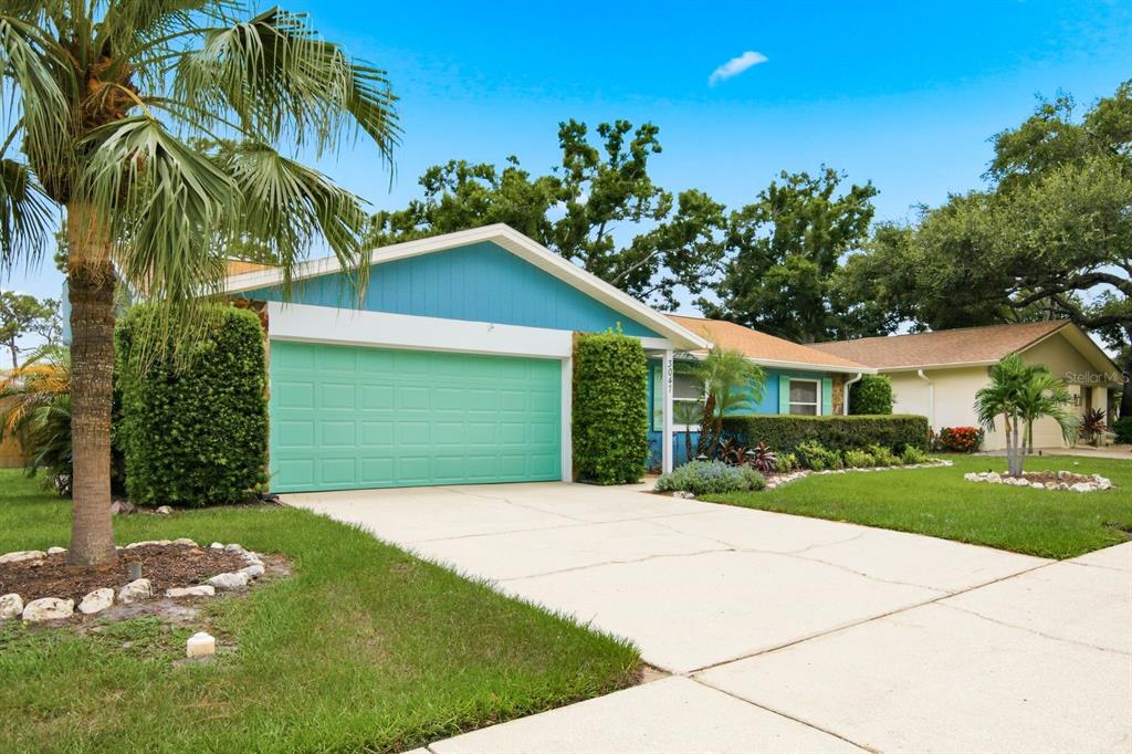 A single-story house with a blue exterior, a teal garage door, and a concrete driveway — 3047 CASCADE DRIVE, CLEARWATER, FL