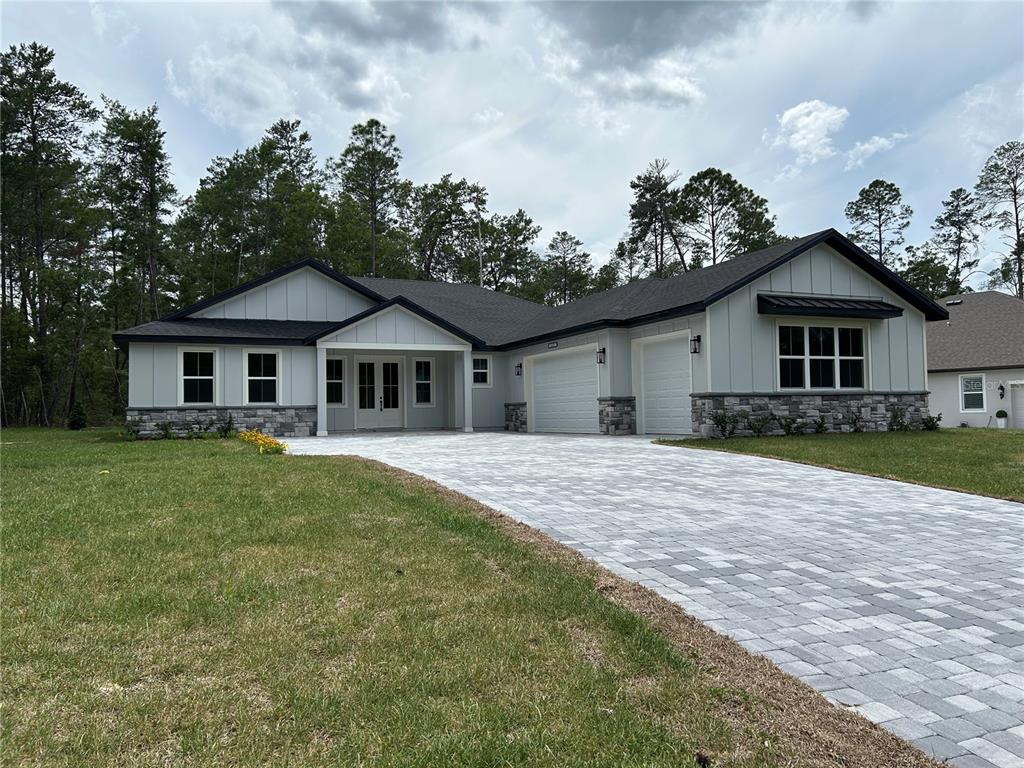 A single-story house with light gray siding, stone accents, and a paved driveway — 7804 N VOYAGER DRIVE, DUNNELLON, FL