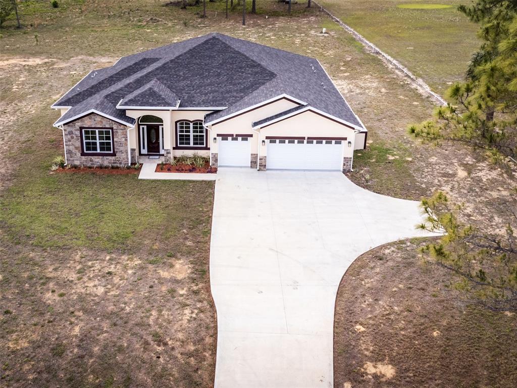 An aerial view of a single-story house with a stone facade and a concrete driveway — 41289 COUNTY ROAD 452, LEESBURG, FL