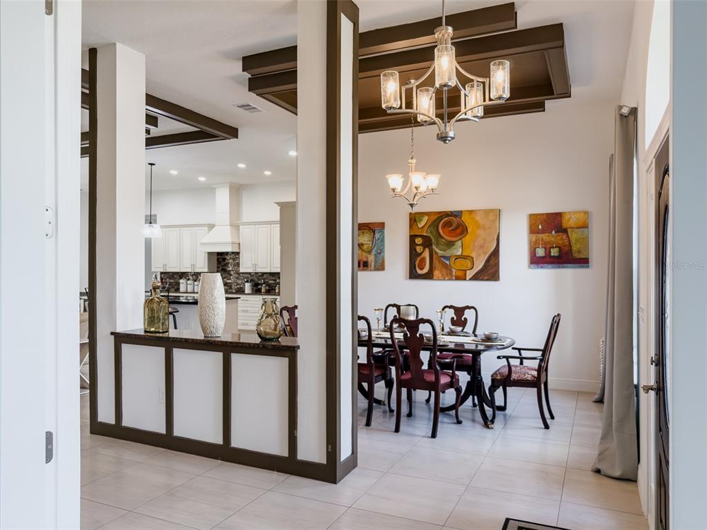 A dining room with a chandelier and coffered ceiling opens to a kitchen with white cabinets — 41289 COUNTY ROAD 452, LEESBURG, FL
