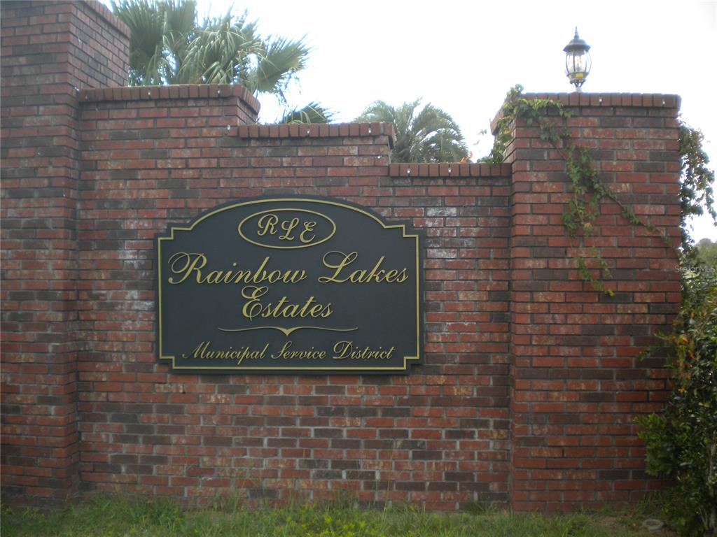 A brick wall features a sign for the Rainbow Lakes Estates Municipal Service District — lot 7 SE 136TH TERRACE, DUNNELLON, FL
