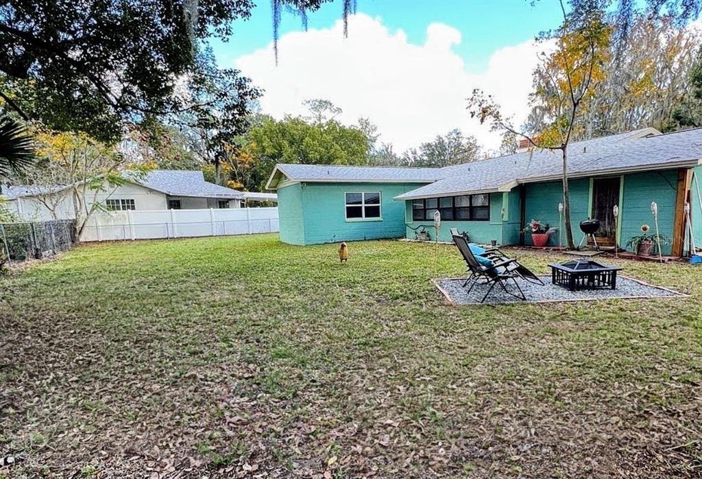 A teal-colored house with a backyard, patio furniture, and a fire pit — 2131 NE 3RD STREET, OCALA, FL