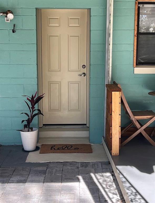 A light-colored front door with a welcome mat sits on a teal concrete block porch — 2131 NE 3RD STREET, OCALA, FL