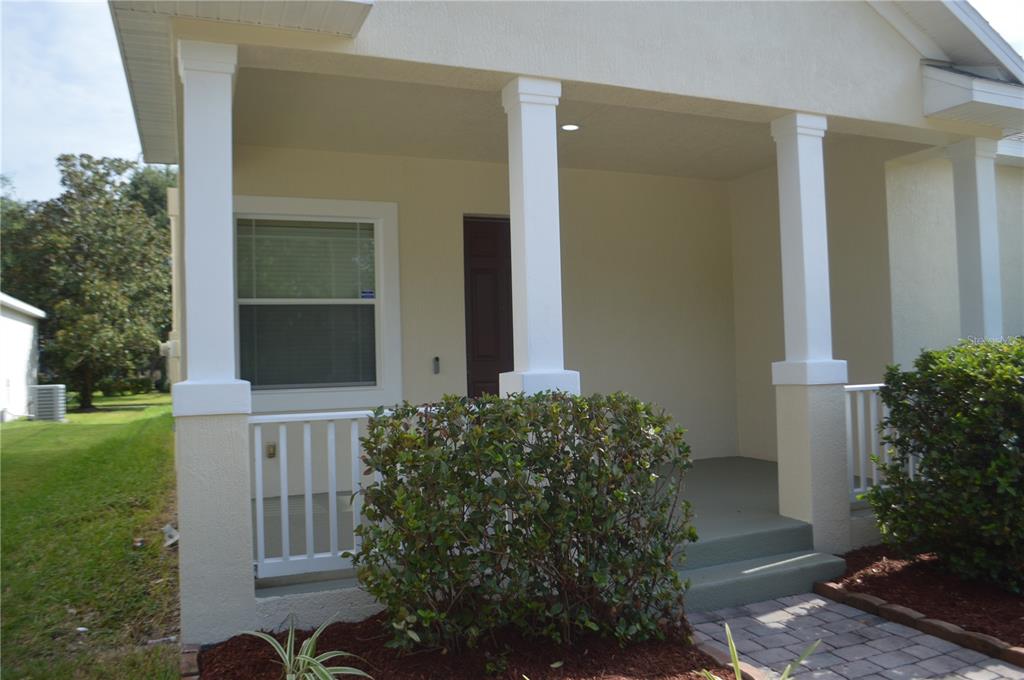 A covered front porch features white columns, a railing, and a paved walkway — 6828 HELMSLEY CIRCLE, WINDERMERE, FL