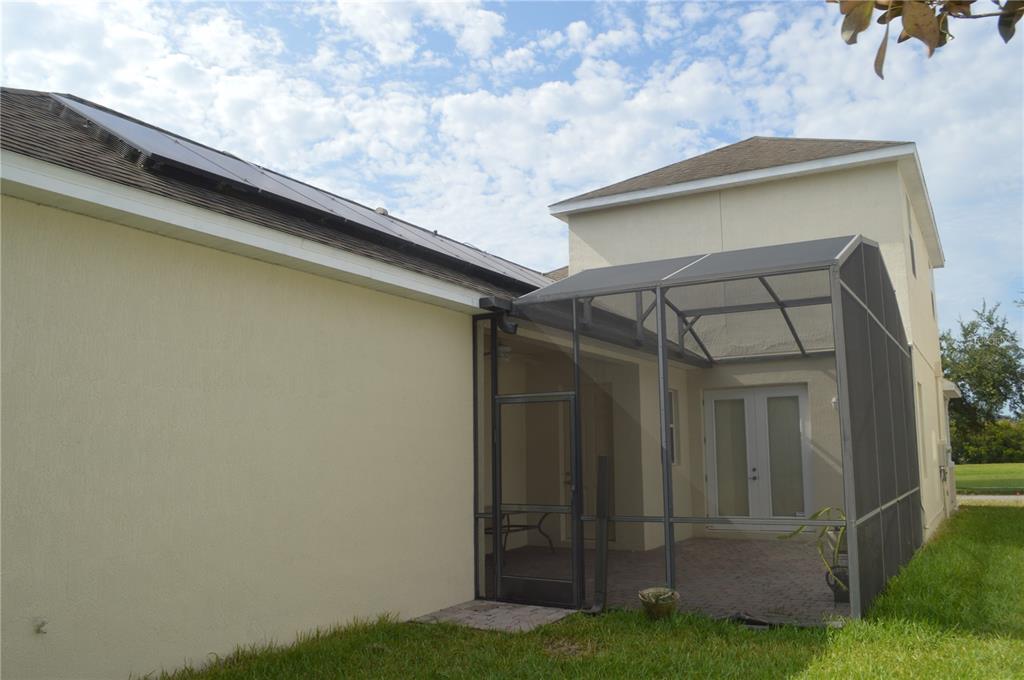 A view of a house exterior featuring a screened-in patio and solar panels on the roof — 6828 HELMSLEY CIRCLE, WINDERMERE, FL
