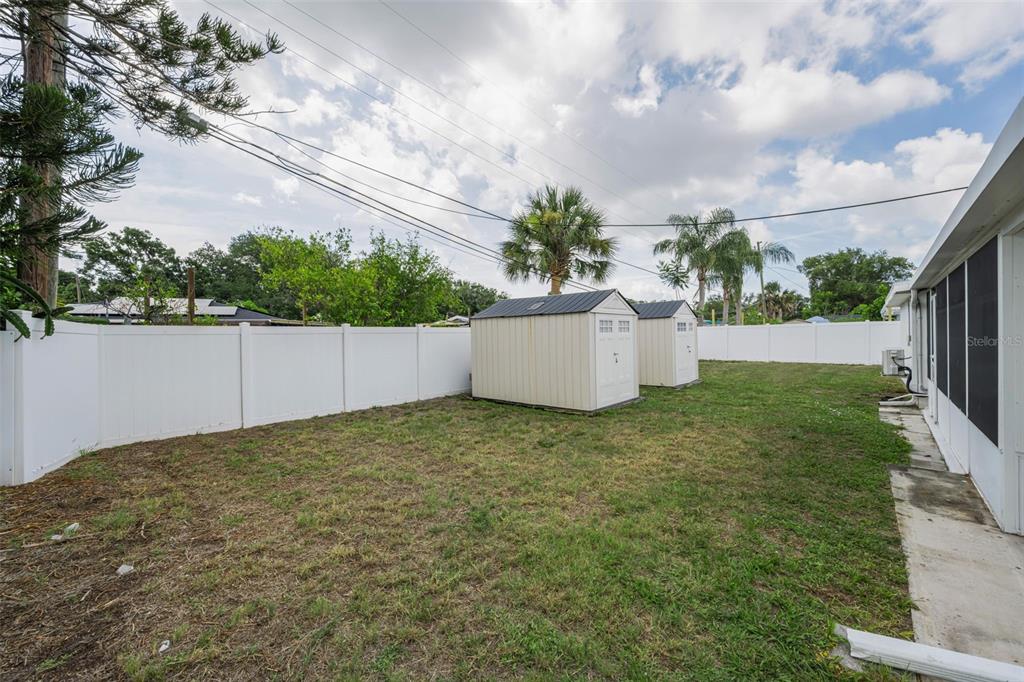 A kitchen features cream-colored cabinets, stainless steel appliances, a tiled backsplash, and dark floor tiles — 6701 ORCHARD DRIVE N, ST PETERSBURG, FL