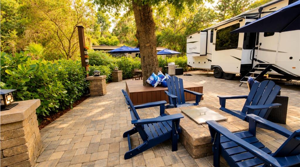 An outdoor patio features wicker furniture with blue cushions under a large black umbrella — 332 BOBCAT LANE, LAKE WALES, FL