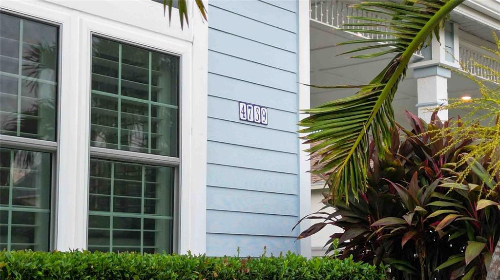 A light blue house exterior features a house number plaque and a nearby palm tree — 4739 PINNACLE DRIVE, BRADENTON, FL