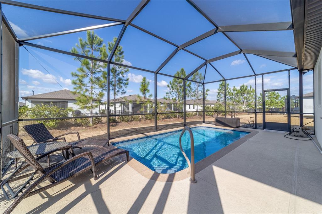 A screened-in patio features a rectangular swimming pool, lounge chairs, and a concrete deck — 9419 SW 53RD PLACE, OCALA, FL