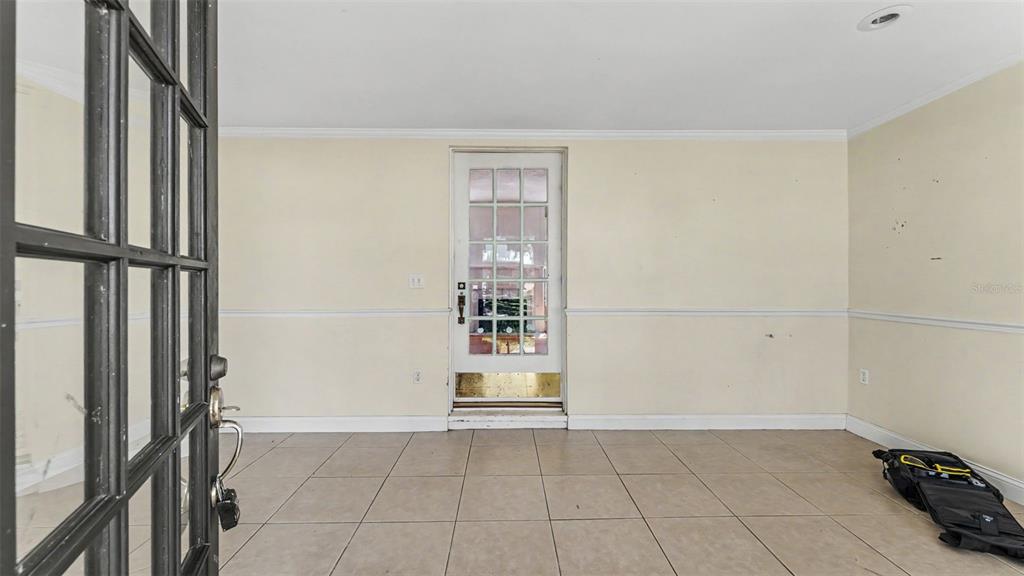 An empty room with beige walls, chair rail molding, and light-colored tile flooring — 2406 FAIRMOUNT AVENUE, LAKELAND, FL