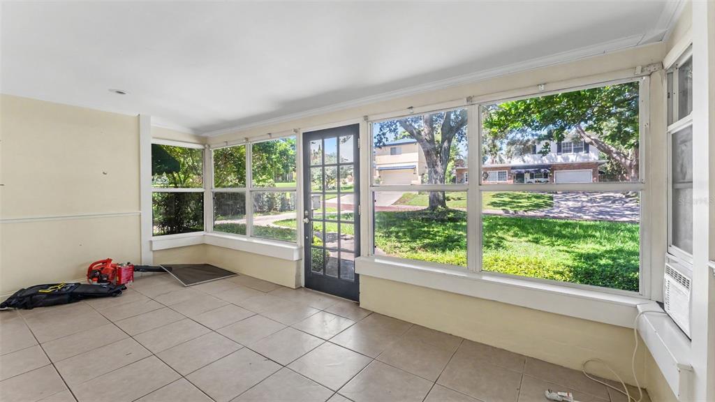A sunroom with tile flooring, large windows, and a glass-paneled door leading to the yard — 2406 FAIRMOUNT AVENUE, LAKELAND, FL