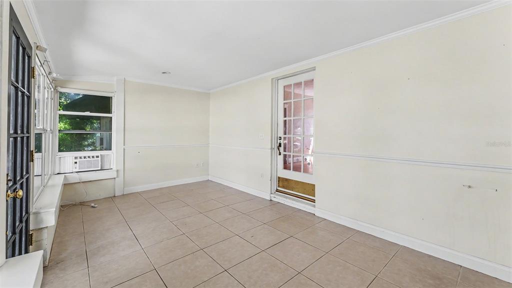 A sunroom with beige tile flooring, white walls, and a glass-paned door leading outside — 2406 FAIRMOUNT AVENUE, LAKELAND, FL