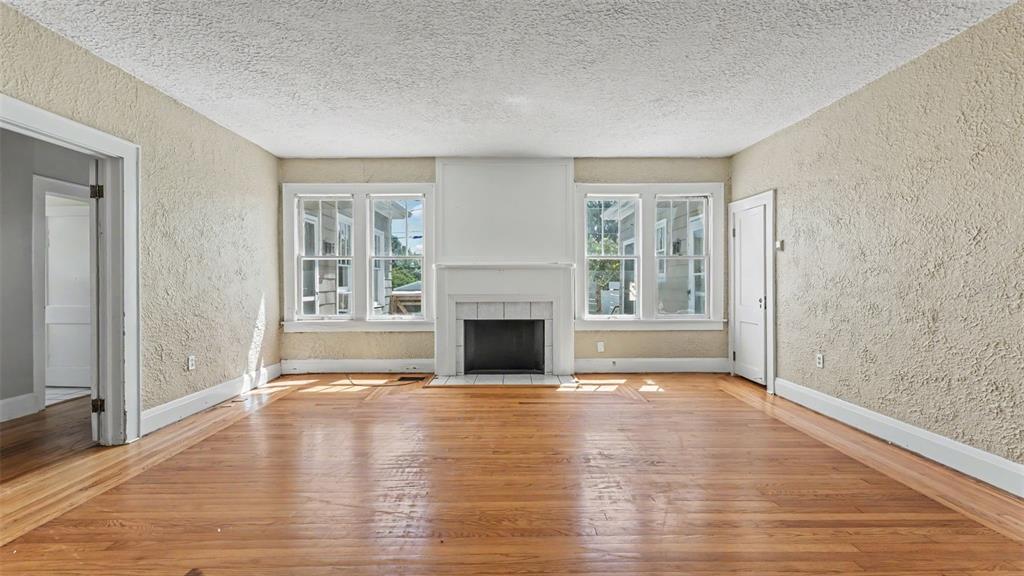 A living room features hardwood floors, textured walls, and a central fireplace with white trim — 2406 FAIRMOUNT AVENUE, LAKELAND, FL