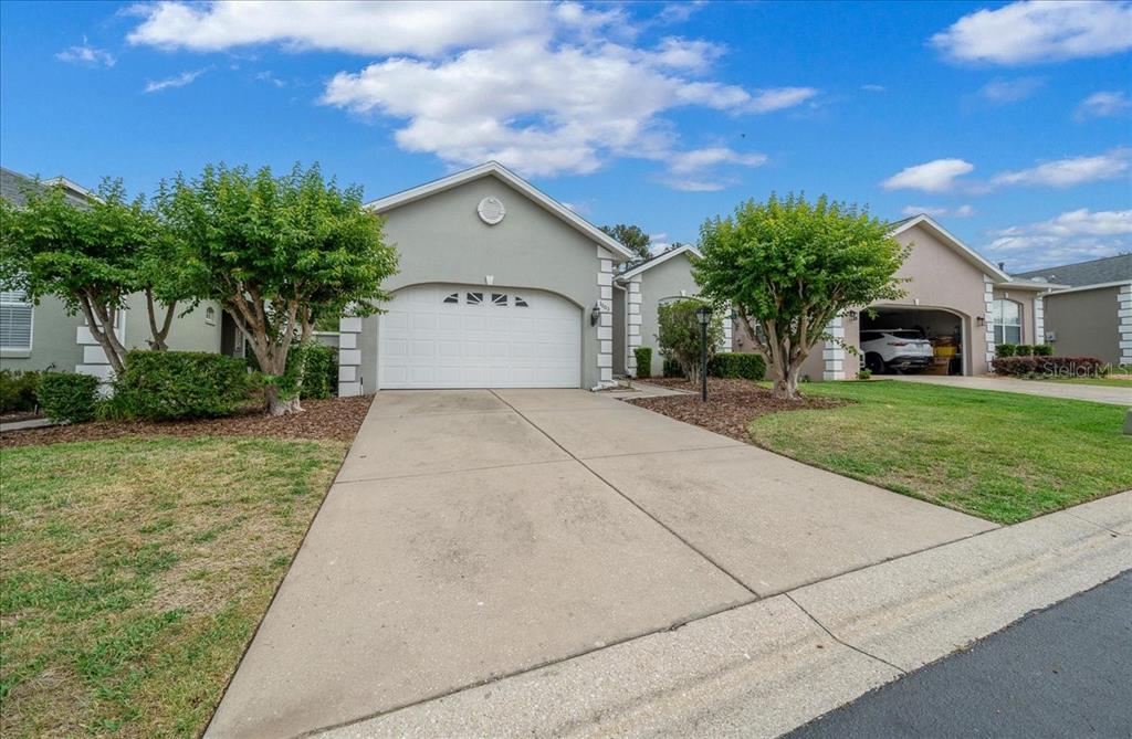 A single-story house with a white garage door, concrete driveway, and two small trees — 3003 SW 41ST PLACE, OCALA, FL