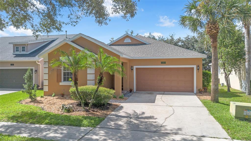 A single-story tan house with a two-car garage, palm trees, and a concrete driveway — 4936 WISE BIRD DRIVE, WINDERMERE, FL