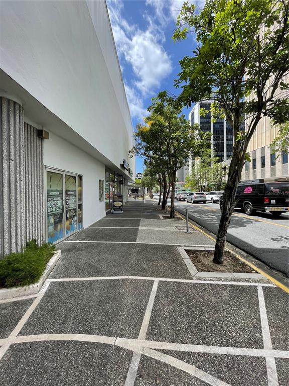 A sidewalk runs alongside a commercial building with glass storefronts and a nearby street — 252 PONCE DE LEON AVE, SAN JUAN, PR
