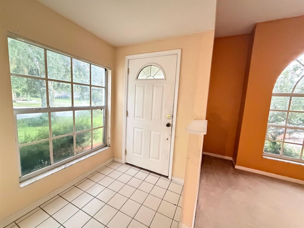 An entryway with white tile flooring, a white front door, and large windows — 24449 PAINTER DRIVE, LAND O LAKES, FL