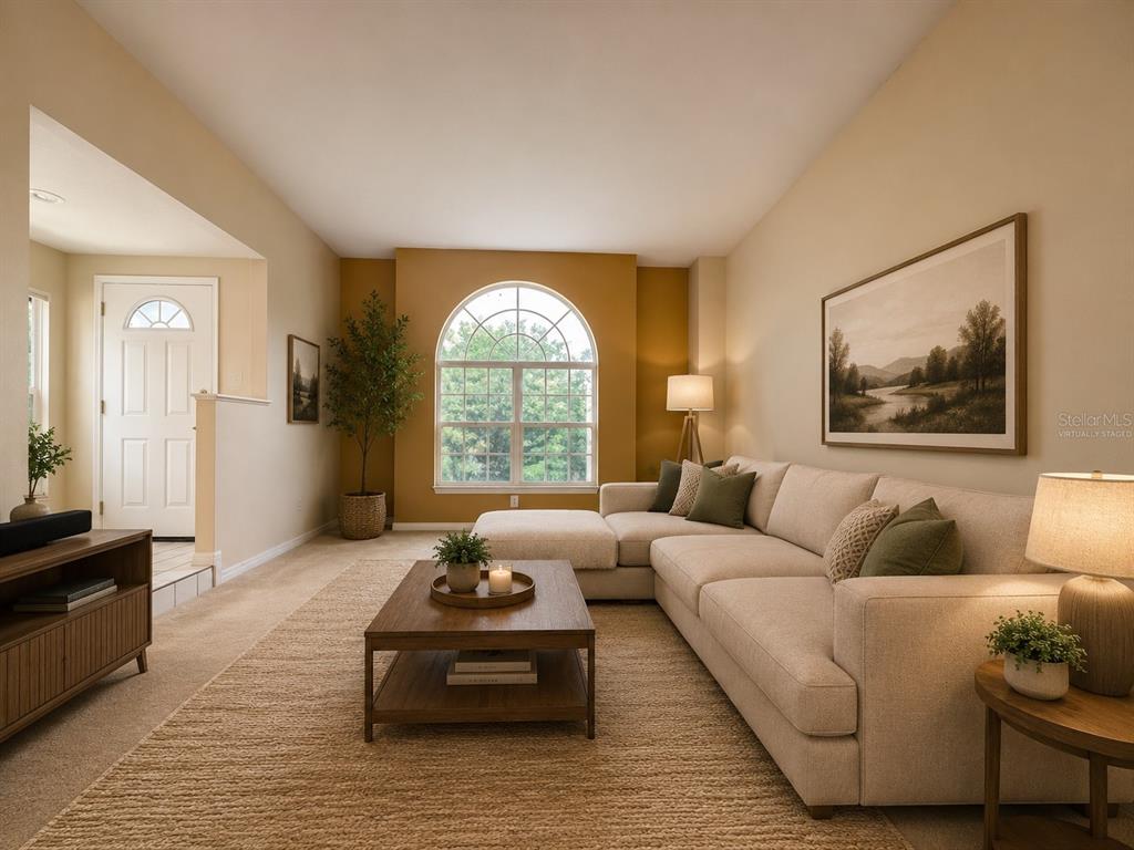 A living room features a beige sectional sofa, a wooden coffee table, and an arched window — 24449 PAINTER DRIVE, LAND O LAKES, FL