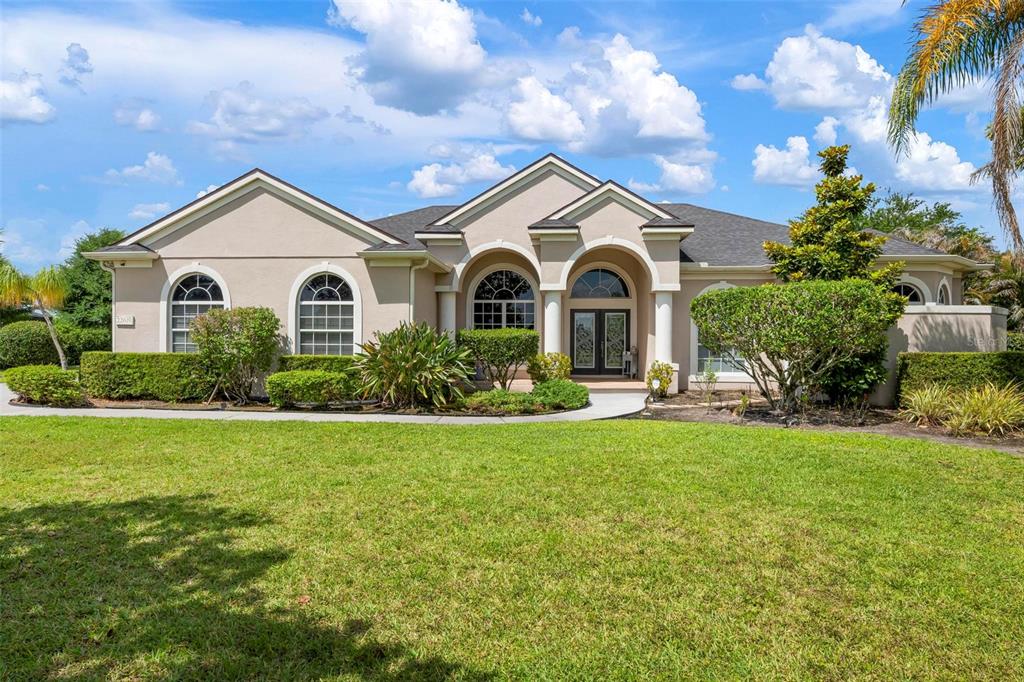 A single-story house with a beige exterior, a concrete driveway, and a manicured lawn — 22610 NIGHT HERON WAY, BRADENTON, FL