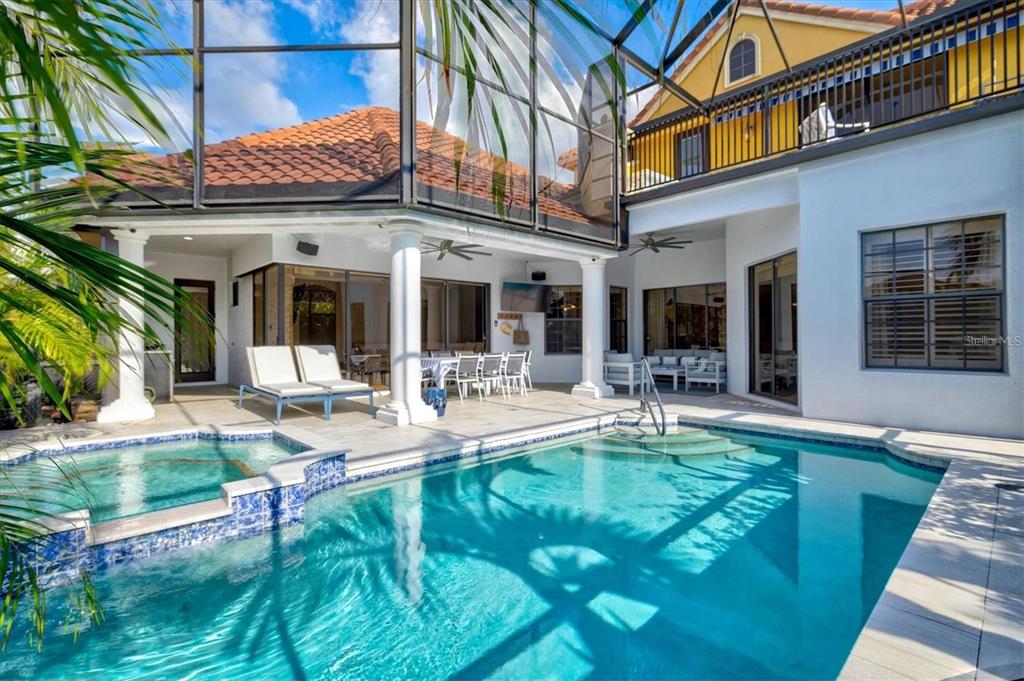 A swimming pool and spa sit on a patio enclosed by a screened-in lanai — 540 FORE DRIVE, BRADENTON, FL