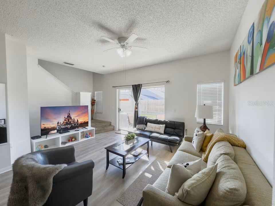A living room features light wood-look flooring, a ceiling fan, and a sliding glass door — 910 PARK TERRACE CIRCLE, KISSIMMEE, FL