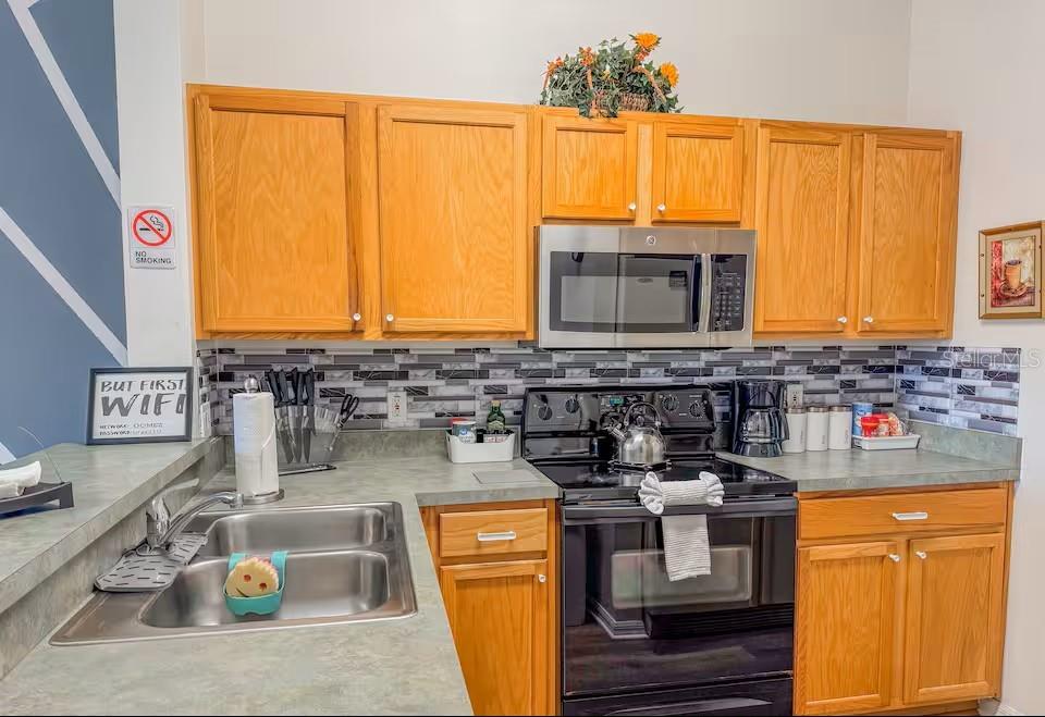 A dining area with a geometric accent wall and a kitchen with a breakfast bar — 910 PARK TERRACE CIRCLE, KISSIMMEE, FL