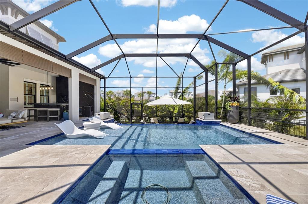 A screened-in patio features a swimming pool with a spa and lounge chairs — 1075 SEAGRAPE DRIVE, RUSKIN, FL