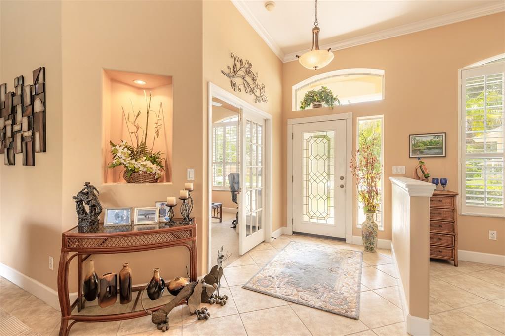 A bright entryway features tile flooring, a glass-paneled front door, and a decorative wall niche — 1283 ROYAL POINTE LANE, ORMOND BEACH, FL