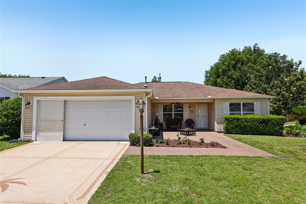 A beige-sided house features a covered patio with outdoor furniture and a fire pit — 1000 KENOVA AVENUE, THE VILLAGES, FL