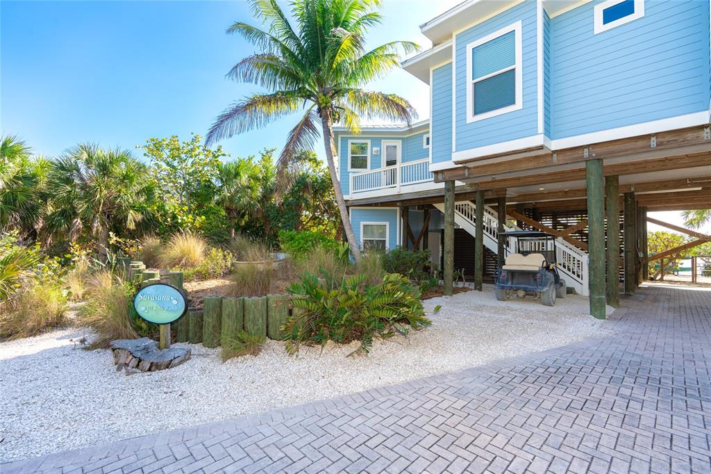 A light blue house on stilts features a palm tree and a golf cart parked underneath — 431 KETTLE HARBOR DRIVE, PLACIDA, FL