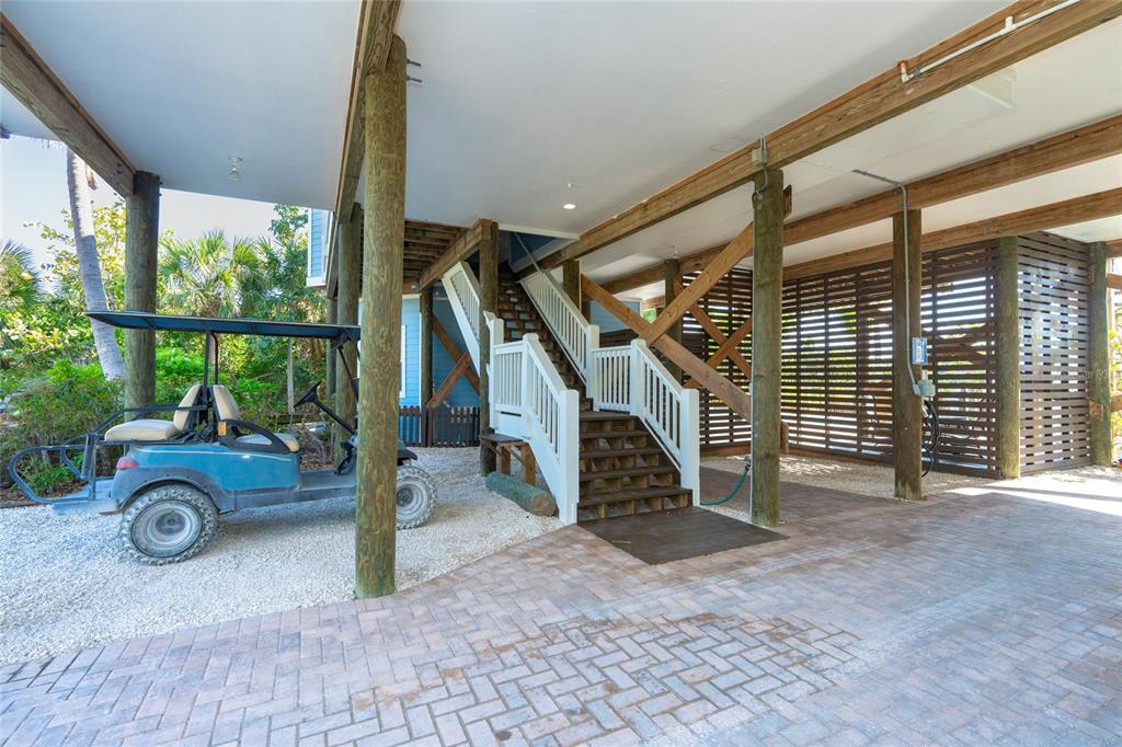 A covered ground-level parking area features a golf cart, wooden stairs, and brick pavers — 431 KETTLE HARBOR DRIVE, PLACIDA, FL