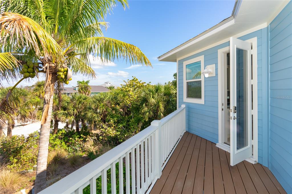 A light blue house features a wooden balcony with a white railing overlooking palm trees — 431 KETTLE HARBOR DRIVE, PLACIDA, FL