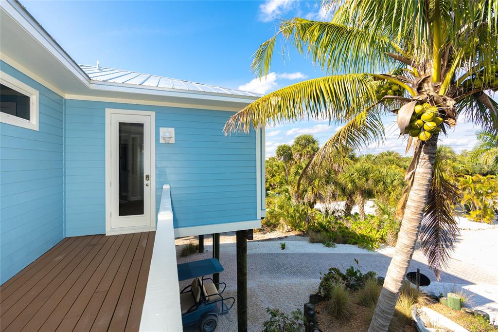 A blue elevated house features a wooden deck, a glass door, and a palm tree — 431 KETTLE HARBOR DRIVE, PLACIDA, FL