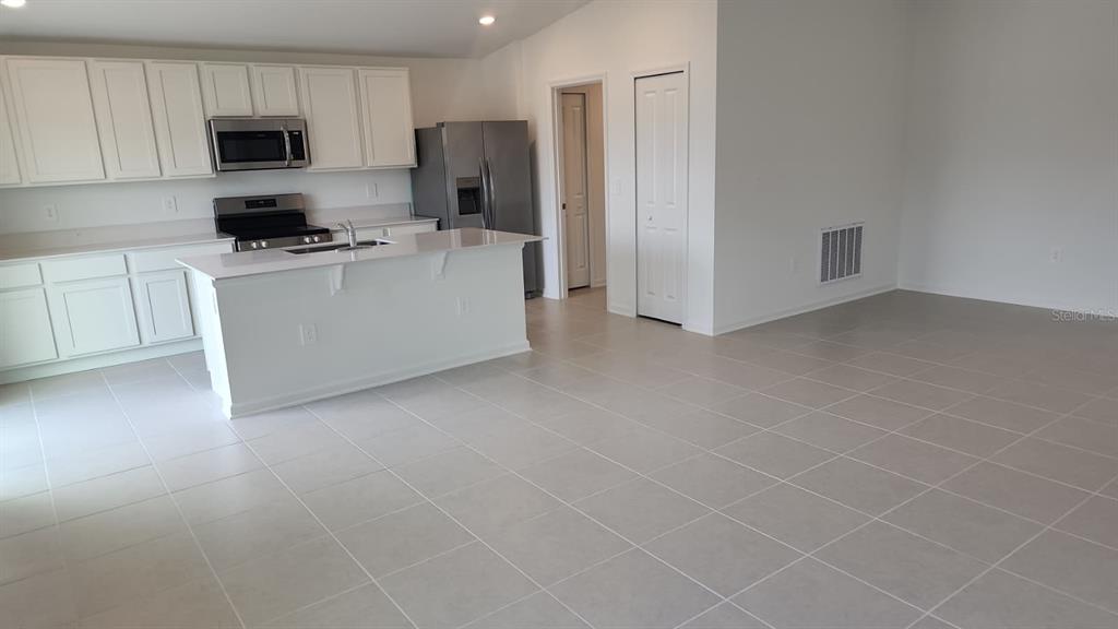 A kitchen with white cabinets, stainless steel appliances, and a central island with tile flooring — 2189 LASSO LOOP, EAGLE LAKE, FL