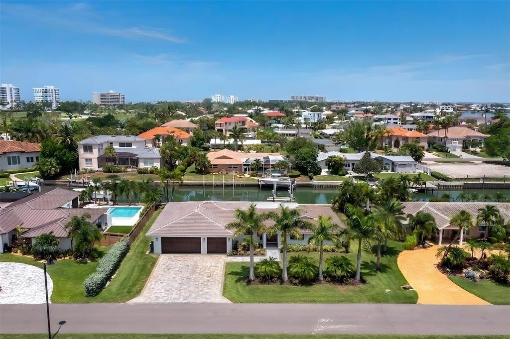An aerial view shows a single-story house with a tiled roof, driveway, and backyard canal — 525 SLOOP LANE, LONGBOAT KEY, FL