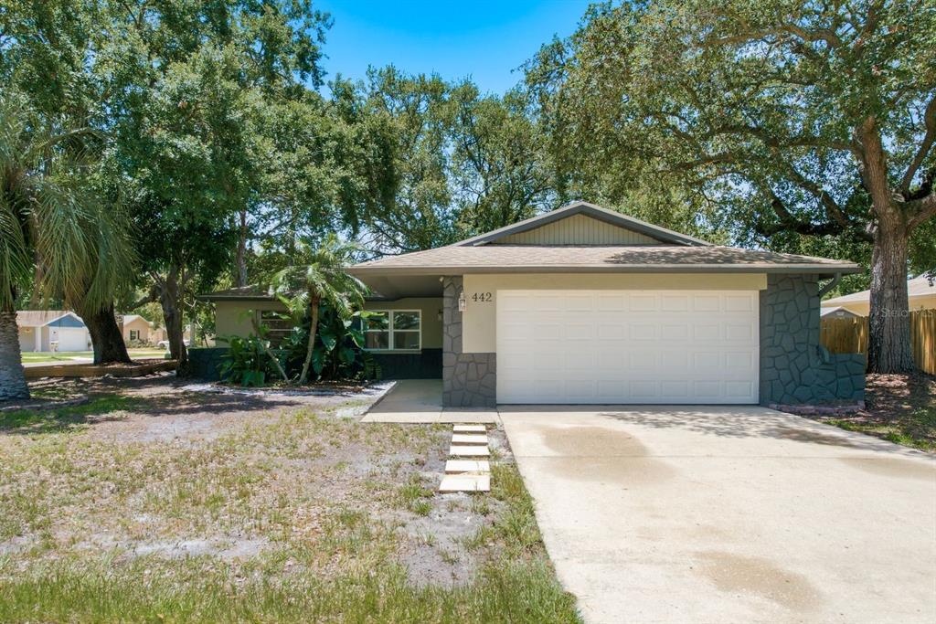 A single-story house with a white garage door, stone accents, and a concrete driveway — 442 EVERGREEN DRIVE, OLDSMAR, FL