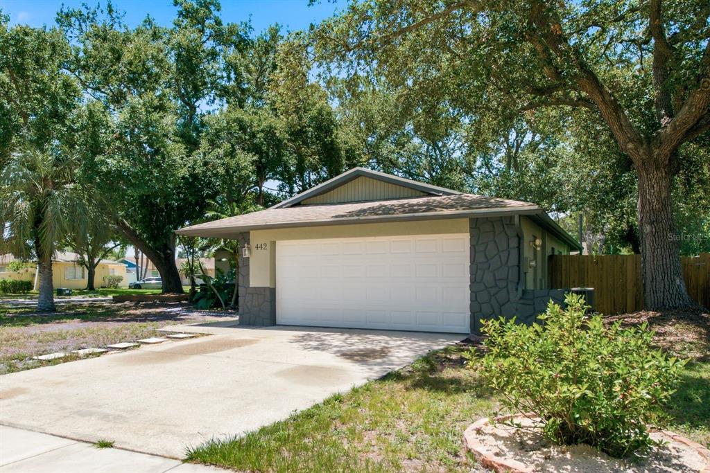 A single-story house with a beige exterior, a two-car garage, and mature trees in front — 442 EVERGREEN DRIVE, OLDSMAR, FL