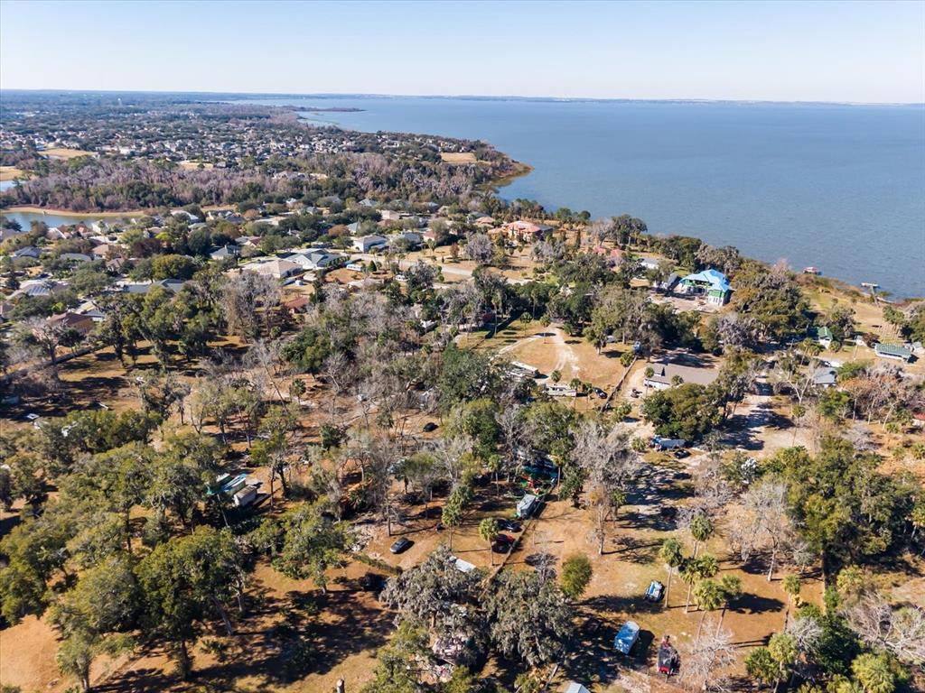 An aerial view shows a wooded residential area along a large lake — WALKER ROAD, APOPKA, FL