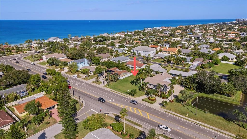 An aerial view shows a vacant grassy lot situated between houses near a coastal beach — CAUSEWAY BOULEVARD, BELLEAIR BEACH, FL