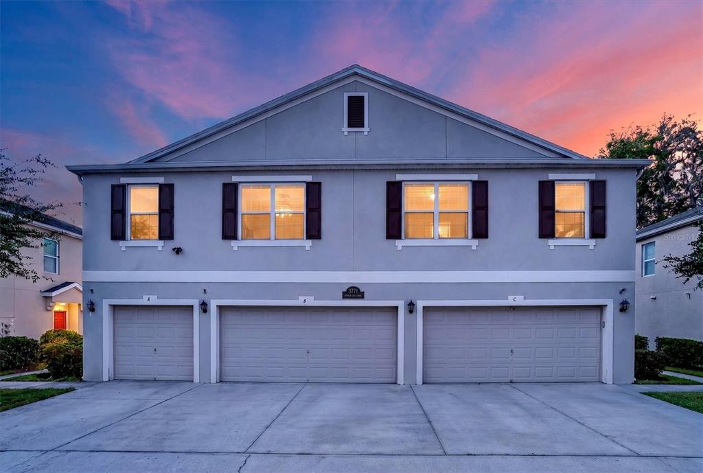 A two-story residential building features three garage doors and four upper-level windows at sunset — 3771 SENECA CLUB LOOP UNIT 59-101 A, ORLANDO, FL
