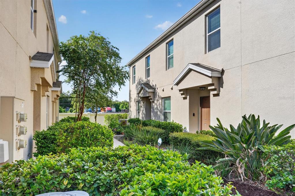 A view of the exterior of two-story townhomes with beige stucco walls and landscaped bushes — 3771 SENECA CLUB LOOP UNIT 59-101 A, ORLANDO, FL